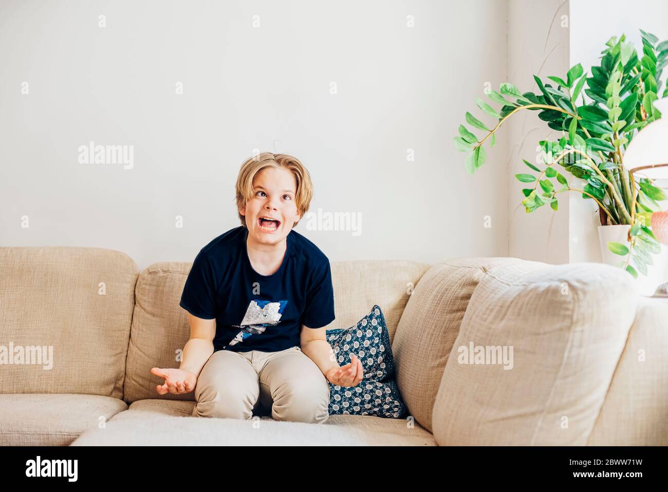 Boy romping around on couch in living room at home Stock Photo