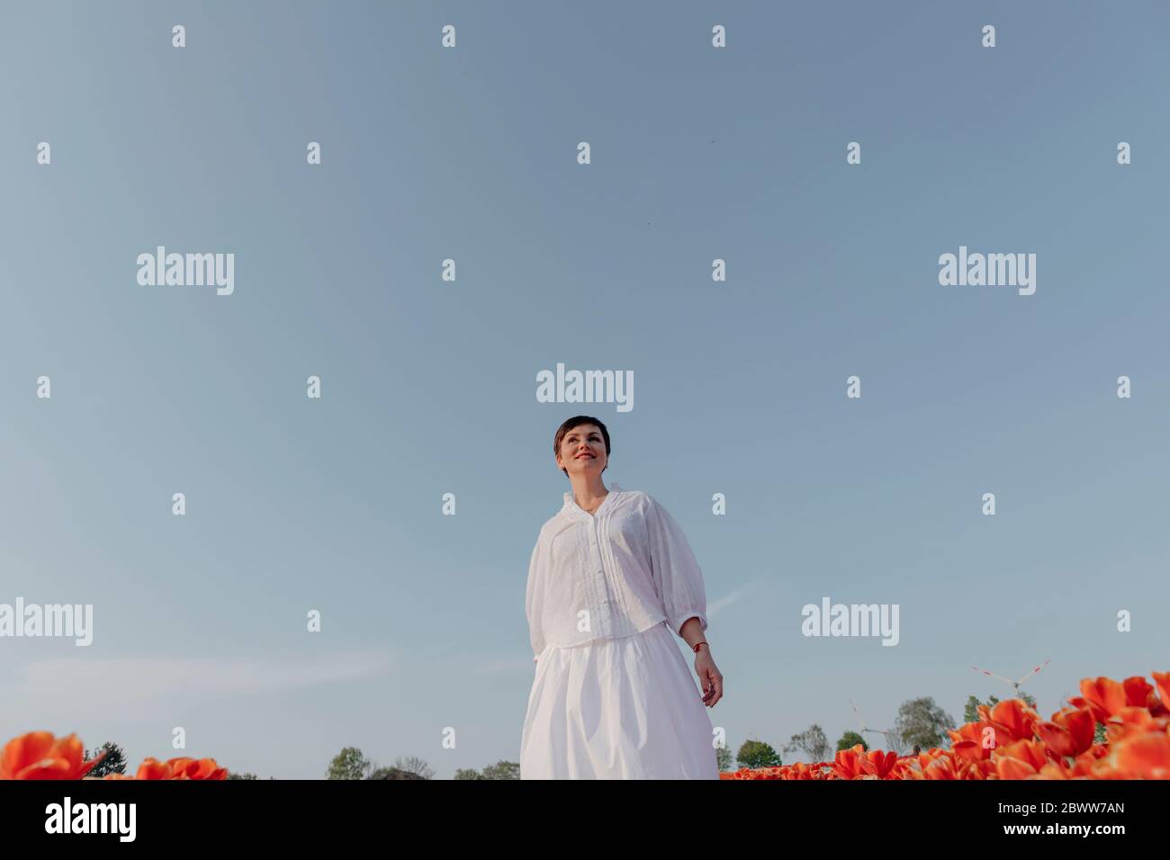 Portrait of smiling woman dressed in white standing tulip field Stock Photo