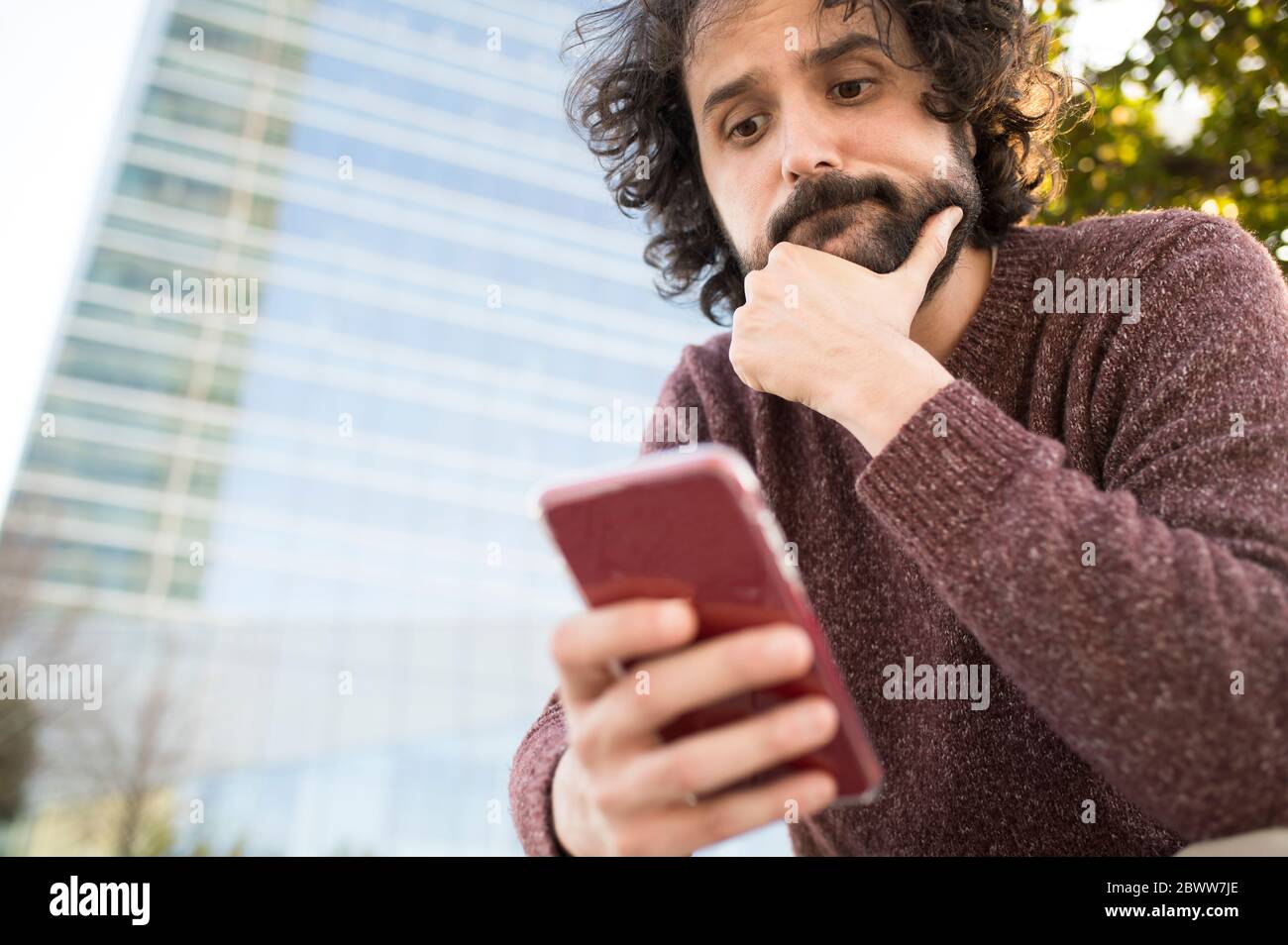 Portrait of bearded man looking at smartphone outdoors Stock Photo