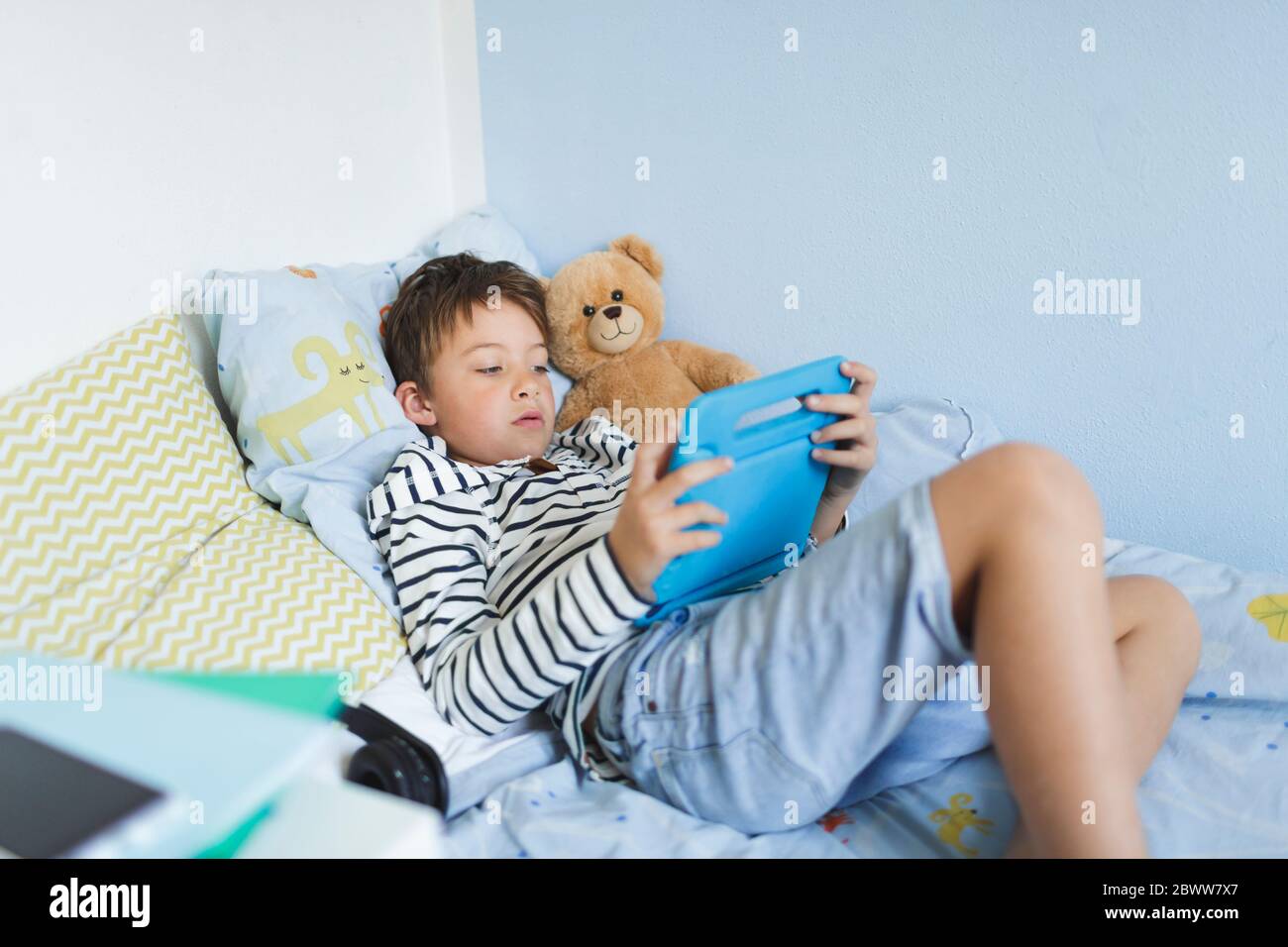 Boy lying in bed using digital tablet Stock Photo