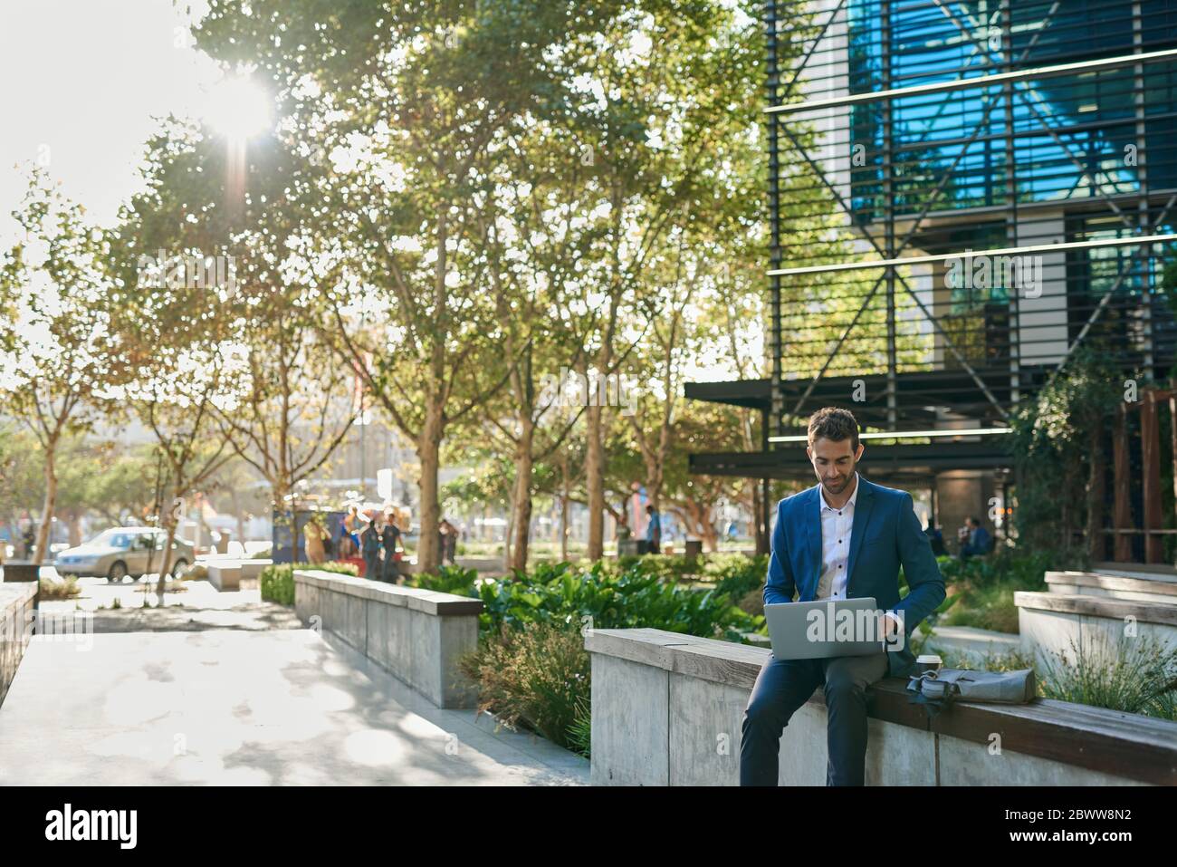 Businessman sitting on a bench outside and using a laptop Stock Photo ...