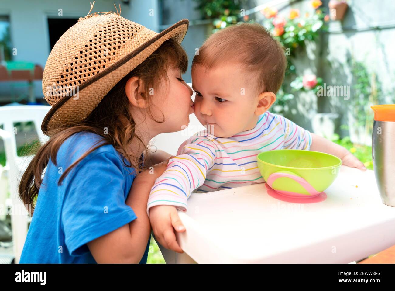 Little girl kissing her younger sister at backyard in spring Stock Photo