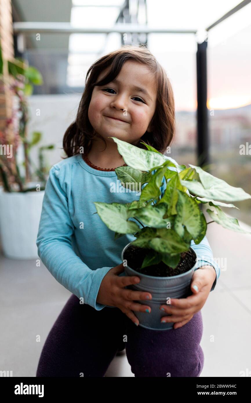 Portrait of smiling little girl on balcony with potted plant Stock ...