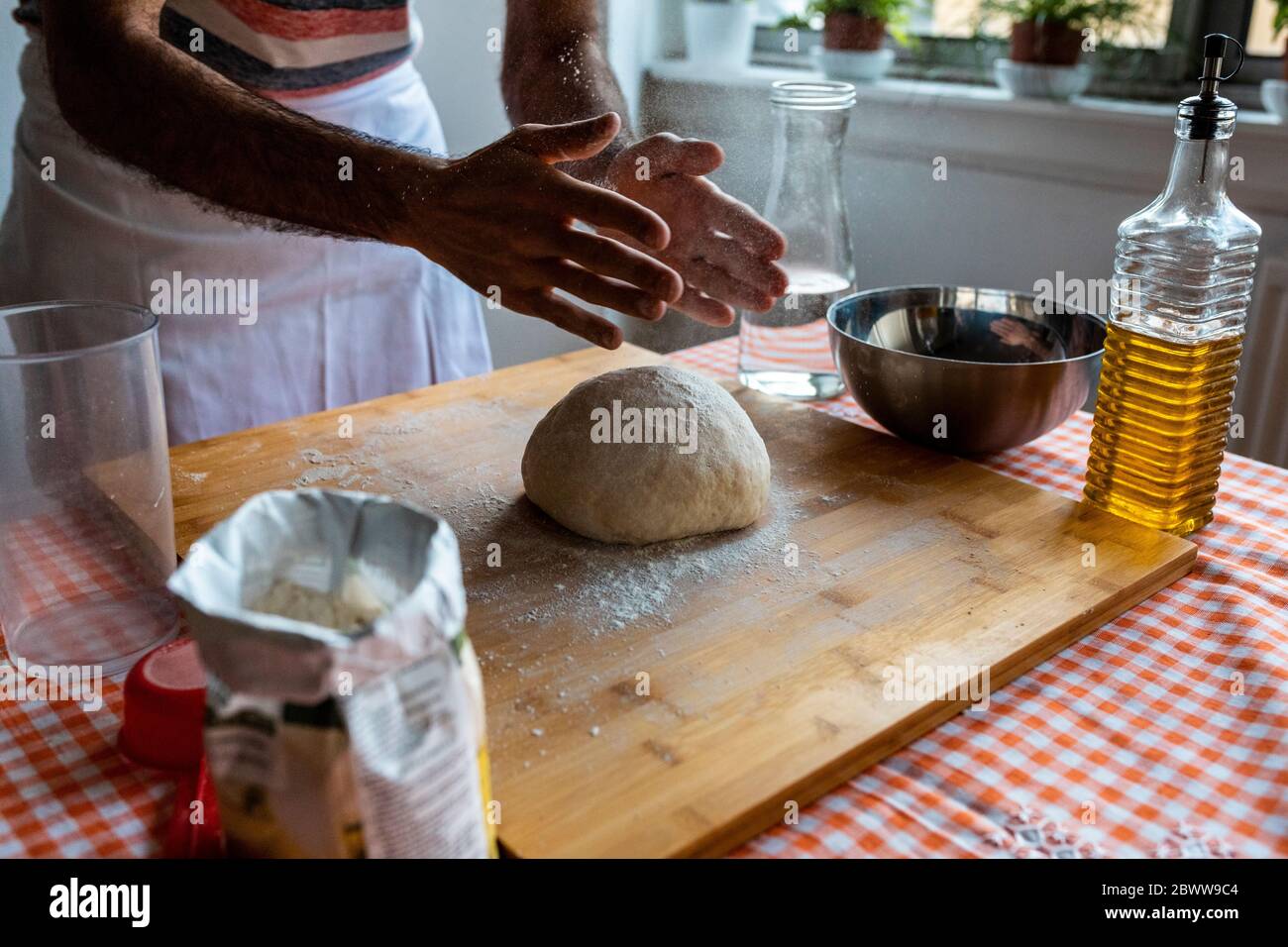 Crop view of man spreading flour on dough ball in the kitchen Stock Photo