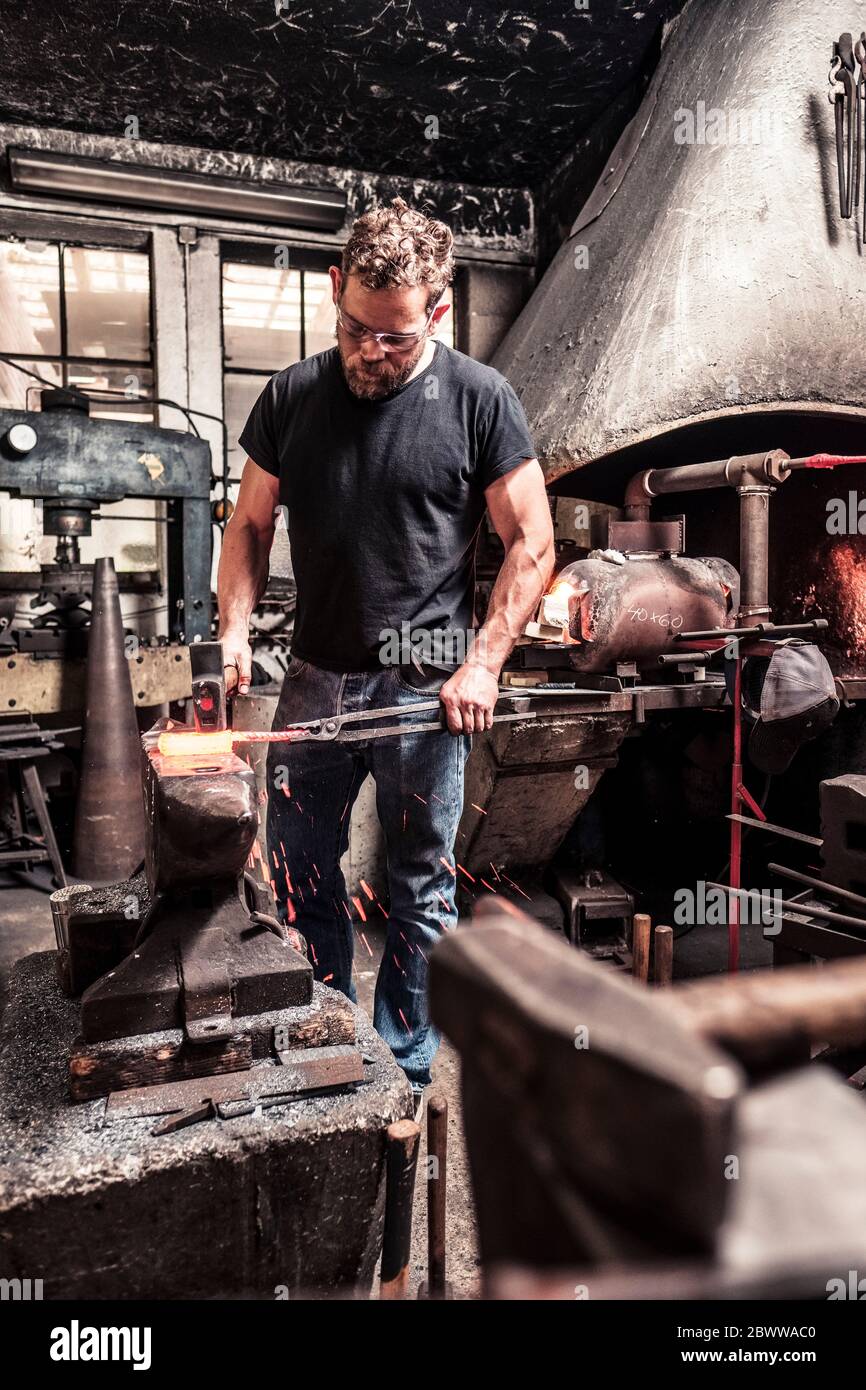 Knife maker working scattering borax over hot damask steel Stock Photo