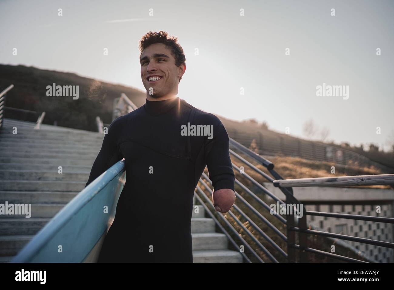 Handicapped surfer with surfboard on stairs Stock Photo