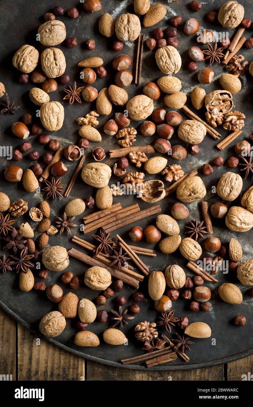 Star anise, cinnamon sticks and various nuts lying on rustic baking sheet Stock Photo