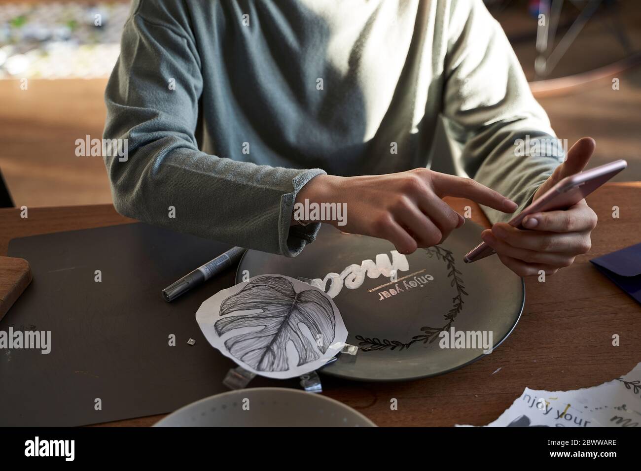 Girl at home using smartphone for a creative online tutorial Stock Photo