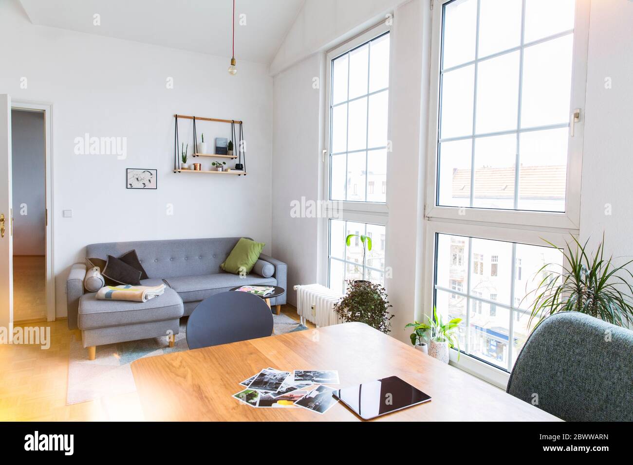 Photographs and tablet on table in bright living room with large windows Stock Photo