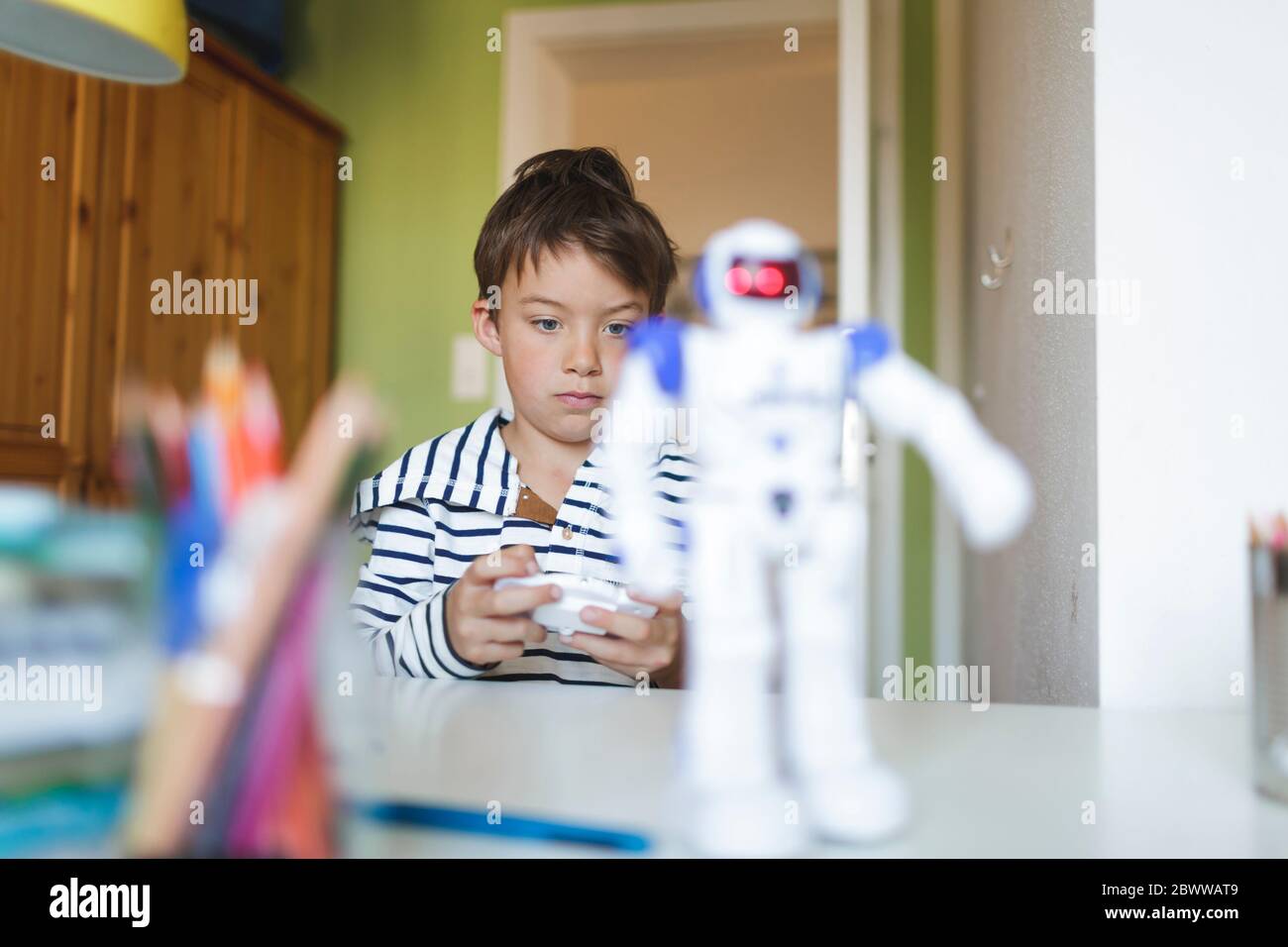 Boy playing with his remote-controlled toy robot at home Stock Photo