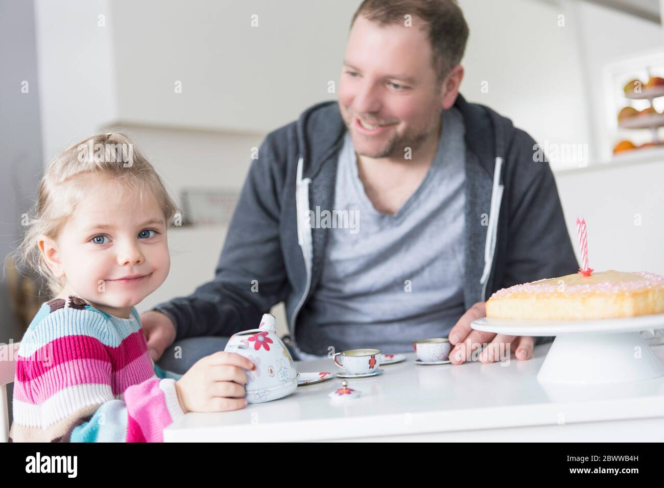 Father and daughter playing with doll's china set Stock Photo