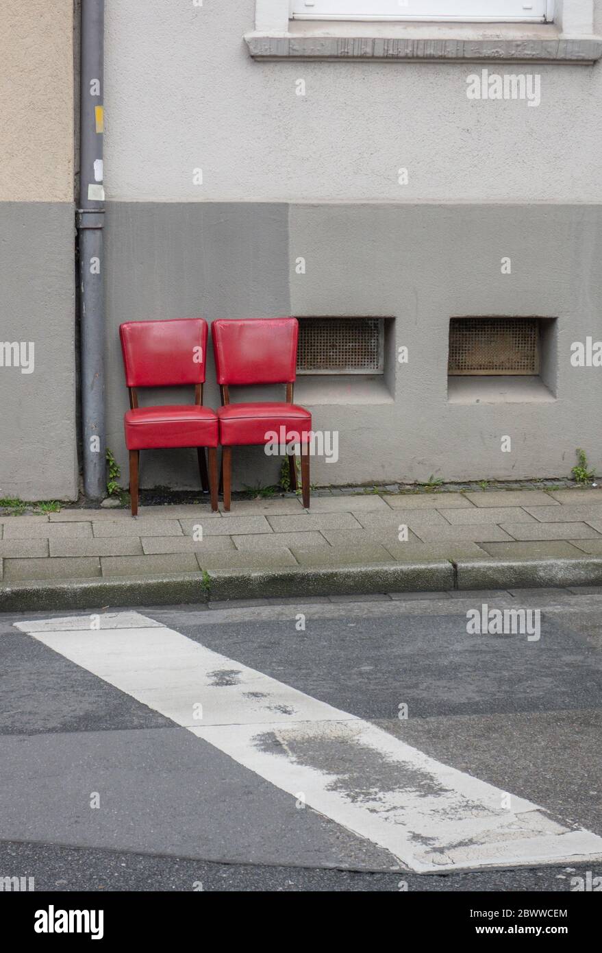 Two red old chairs standing side by side on pavement Stock Photo