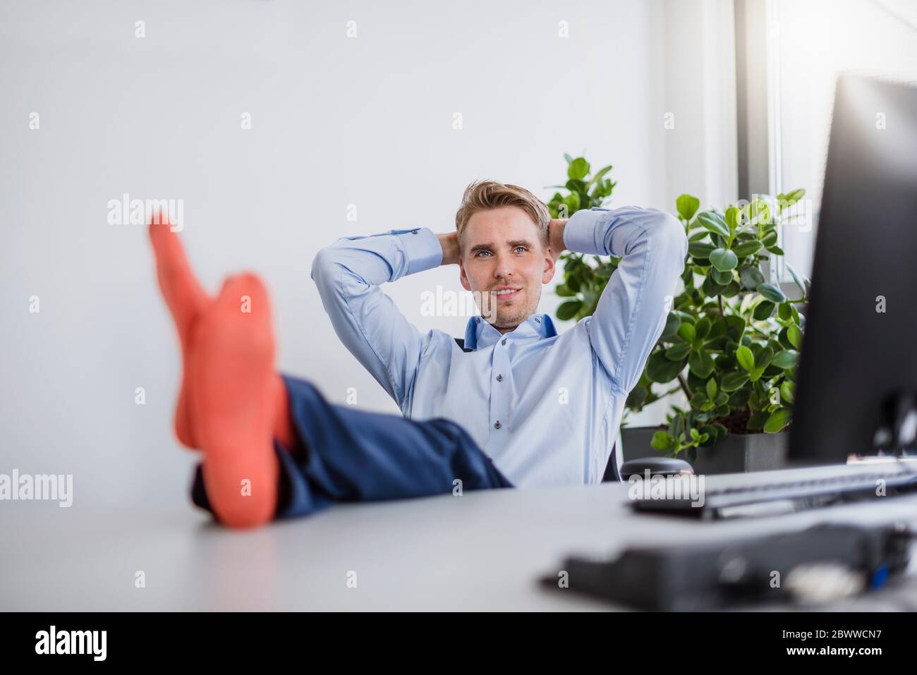 Smiling businessman sitting in office with feet on desk Stock Photo - Alamy