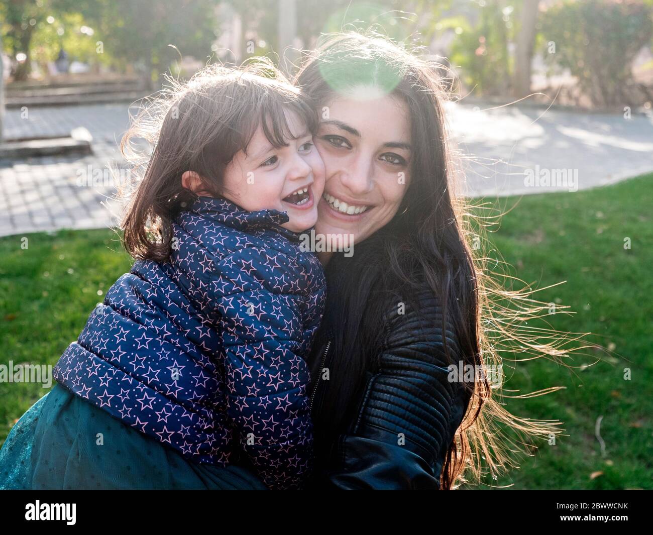 Portrait of happy little girl face to face with her mother outdoors Stock Photo