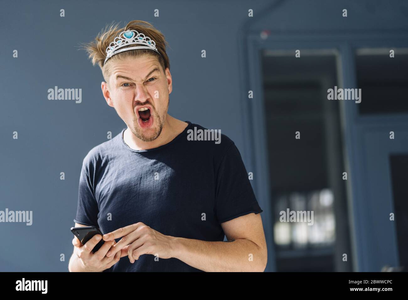 Portrait of a screaming man wearing a tiara Stock Photo