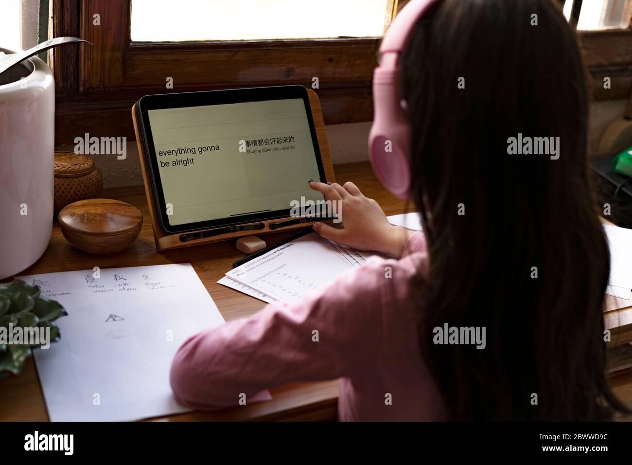 Girl wearing headphones translating languages on digital tablet while learning comics at home Stock Photo