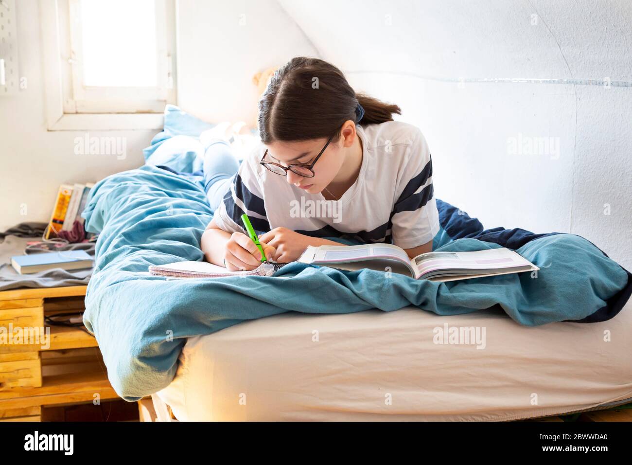 Girl lying on bed doing homework Stock Photo Alamy