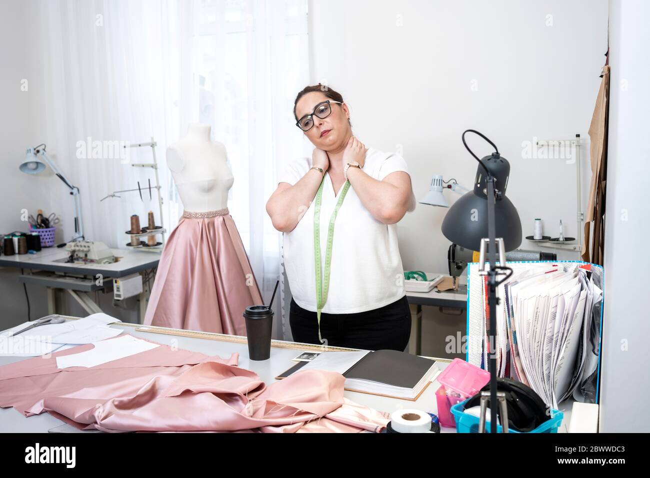 Seamstress with neck pain in tailor shop Stock Photo