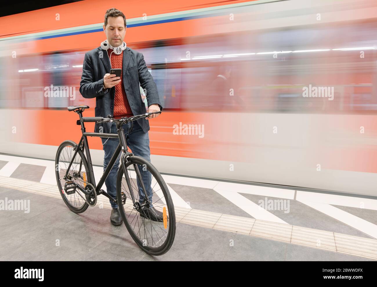 Businessman with bicycle using phone while walking on platform by
