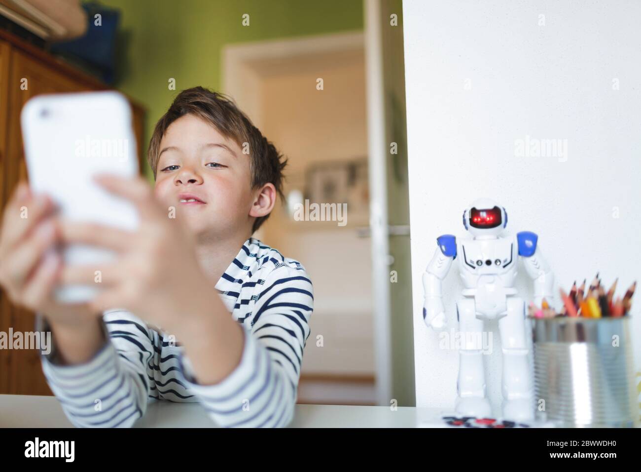 Boy doing homeschooling and using smartphone at home Stock Photo