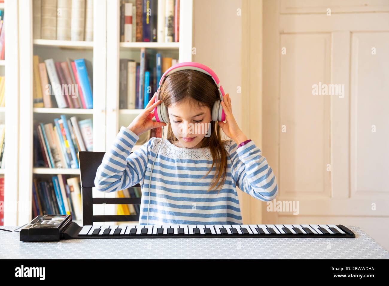 Girl playing roll piano at home Stock Photo