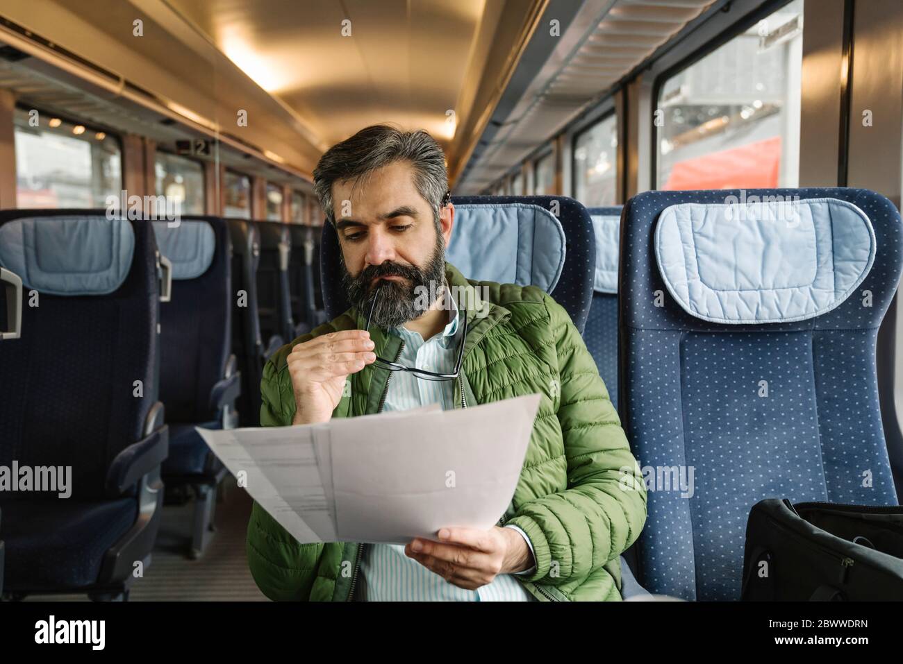 Man sitting in train reading documents Stock Photo