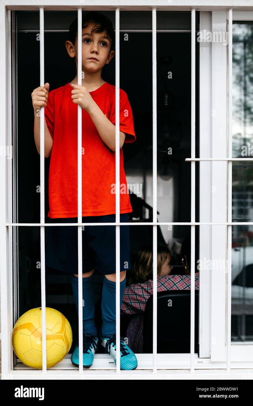 Boy with soccer ball at the window without being able to leave the