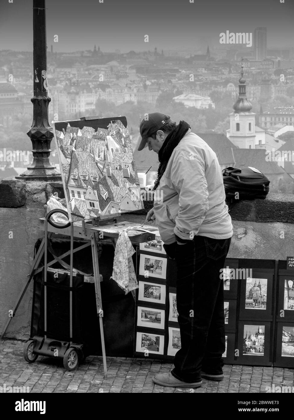 A street artist sells paintings at the Prague Castle - Pra?sk? Hrad with the city skyline. The castle is official office of the President of Czech Rep Stock Photo