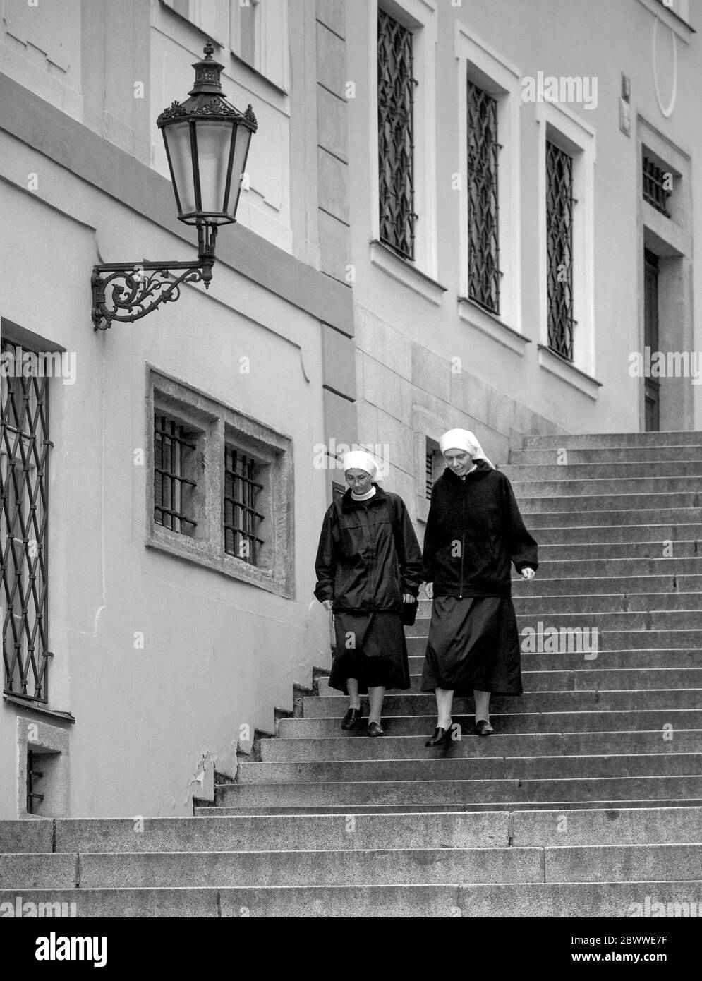 Nuns walk down steep steps at the Prague Castle - Pra?sk? Hrad with the city skyline. The castle is official office of the President of Czech Republic Stock Photo
