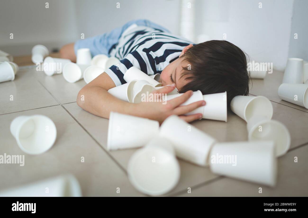 Little boy lying on the floor between white paper cups Stock Photo - Alamy