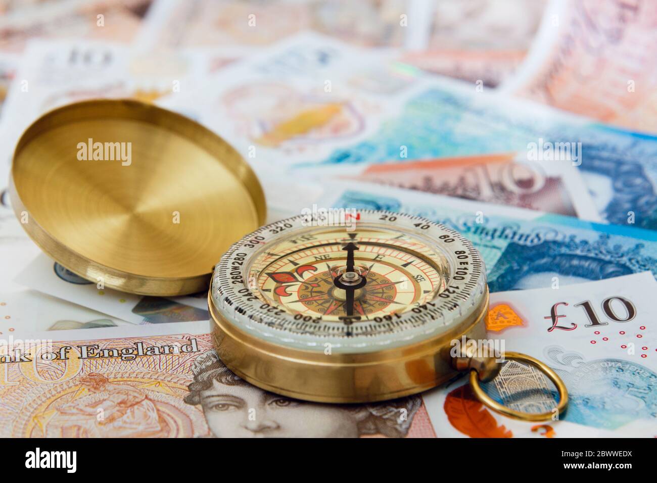 A compass on Sterling money £ ten and five pound notes pounds GBP to illustrate future of British economy. Change direction concept England UK Britain Stock Photo