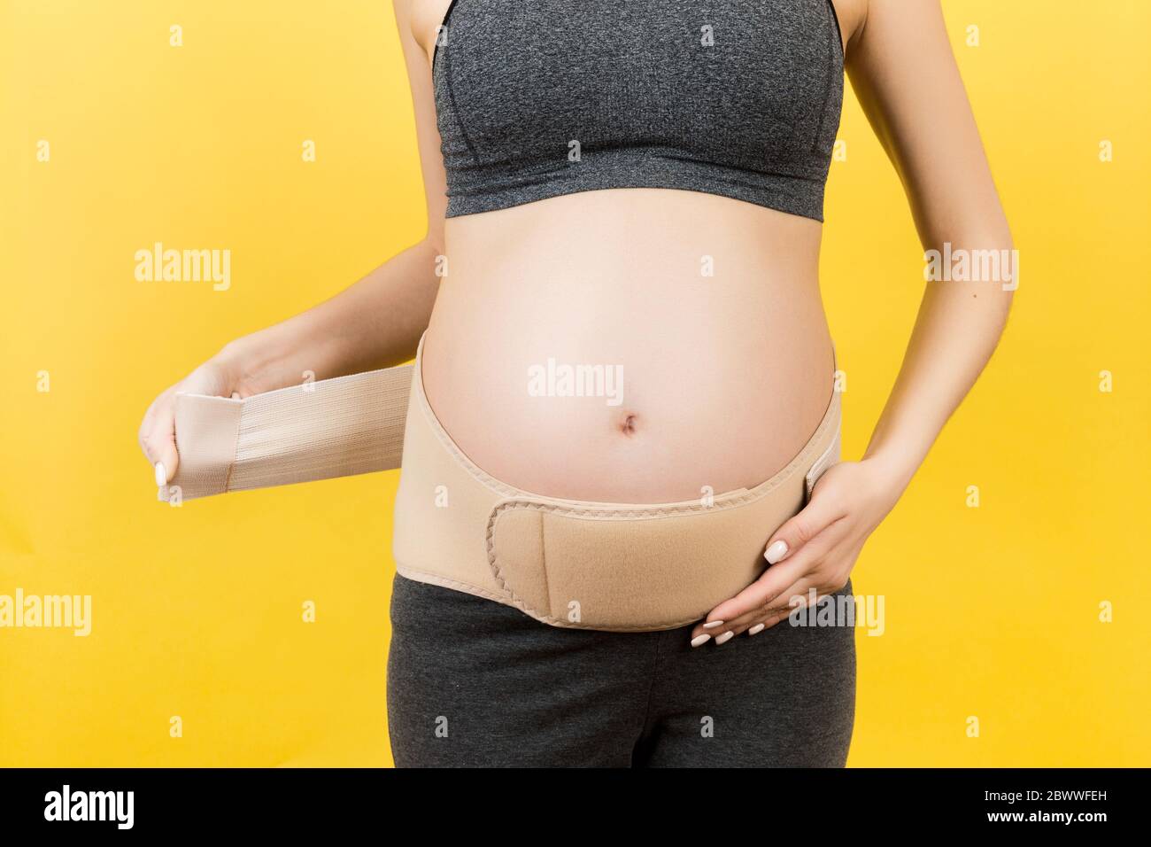 Close up of pregnant woman dressing pregnancy corset on the third