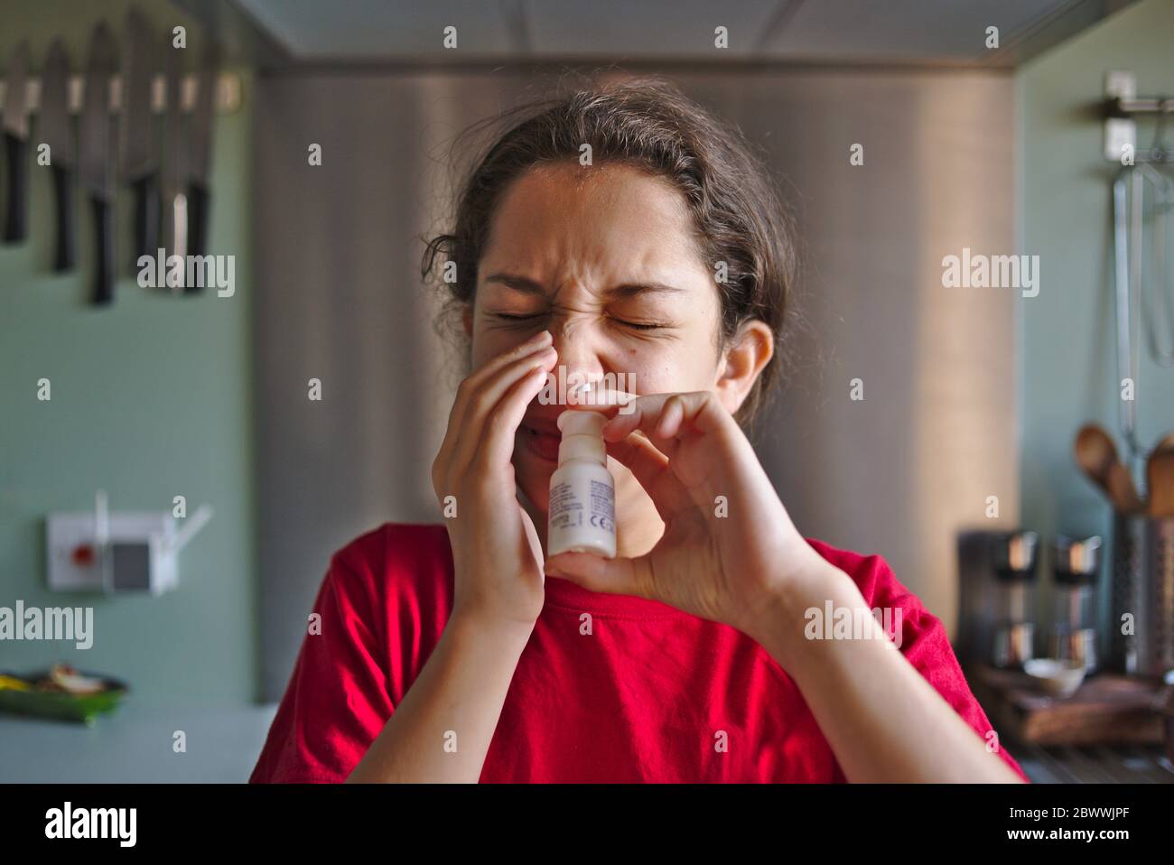 Child hay fever sufferer using nasal spray treatment for some relief from the symptoms of the allergy. Stock Photo