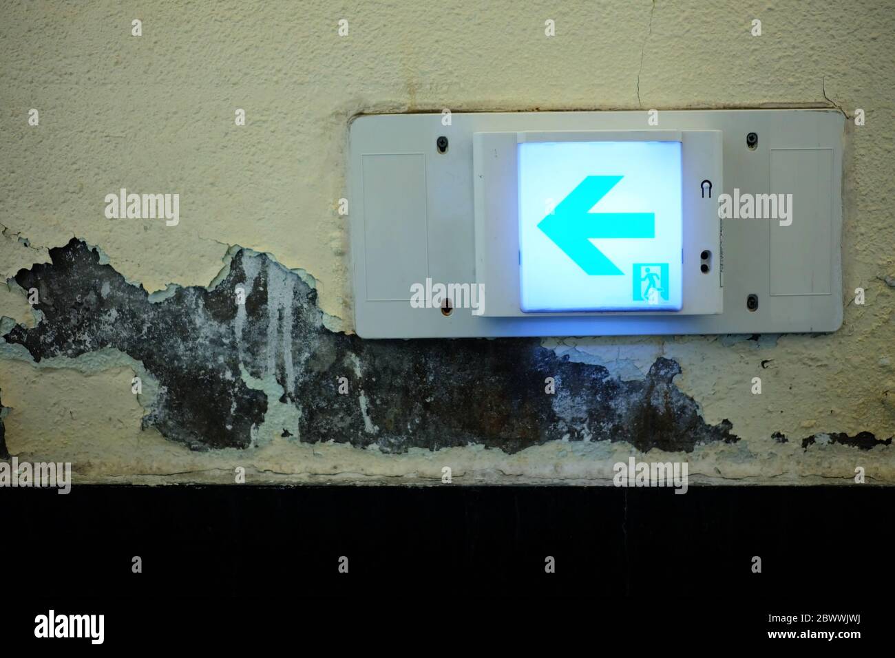 Emergency Exit Sign on Grunge Concrete Wall Background. Stock Photo