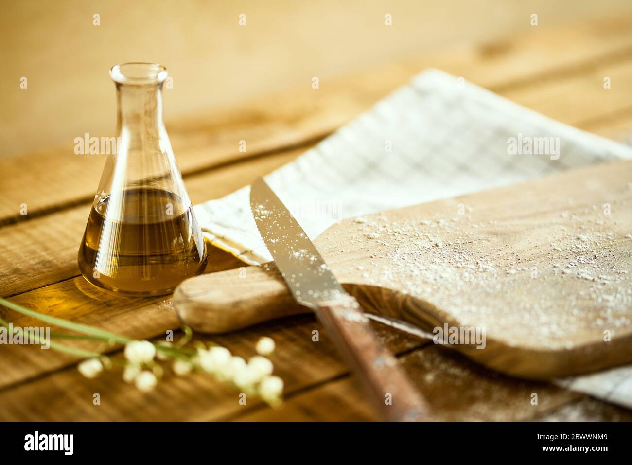 olive oil, knife and cutting board on wooden table Stock Photo