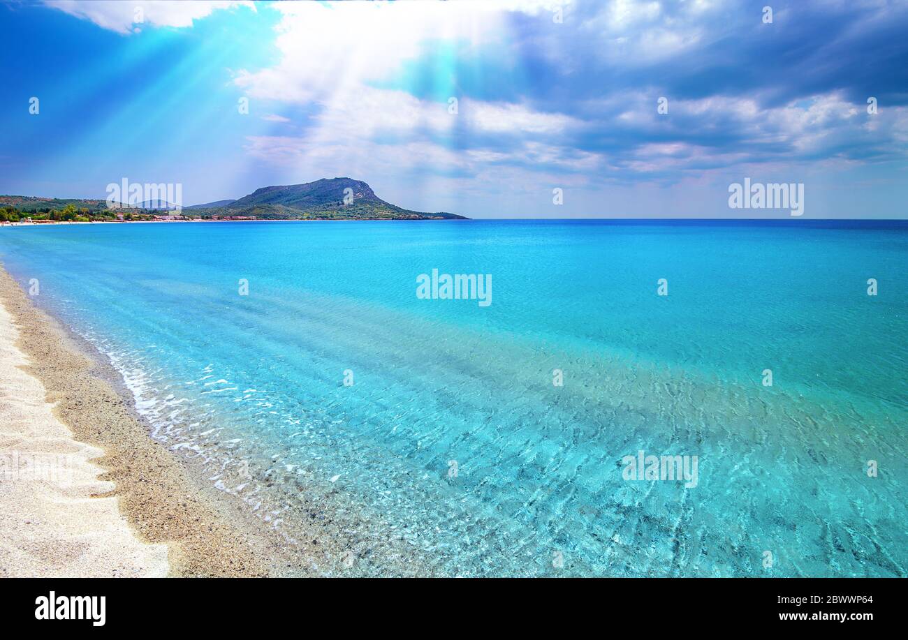 Blue sky, white clouds, sun rays, clear sea water background. Toroni beach, Sithonia, Greece Stock Photo