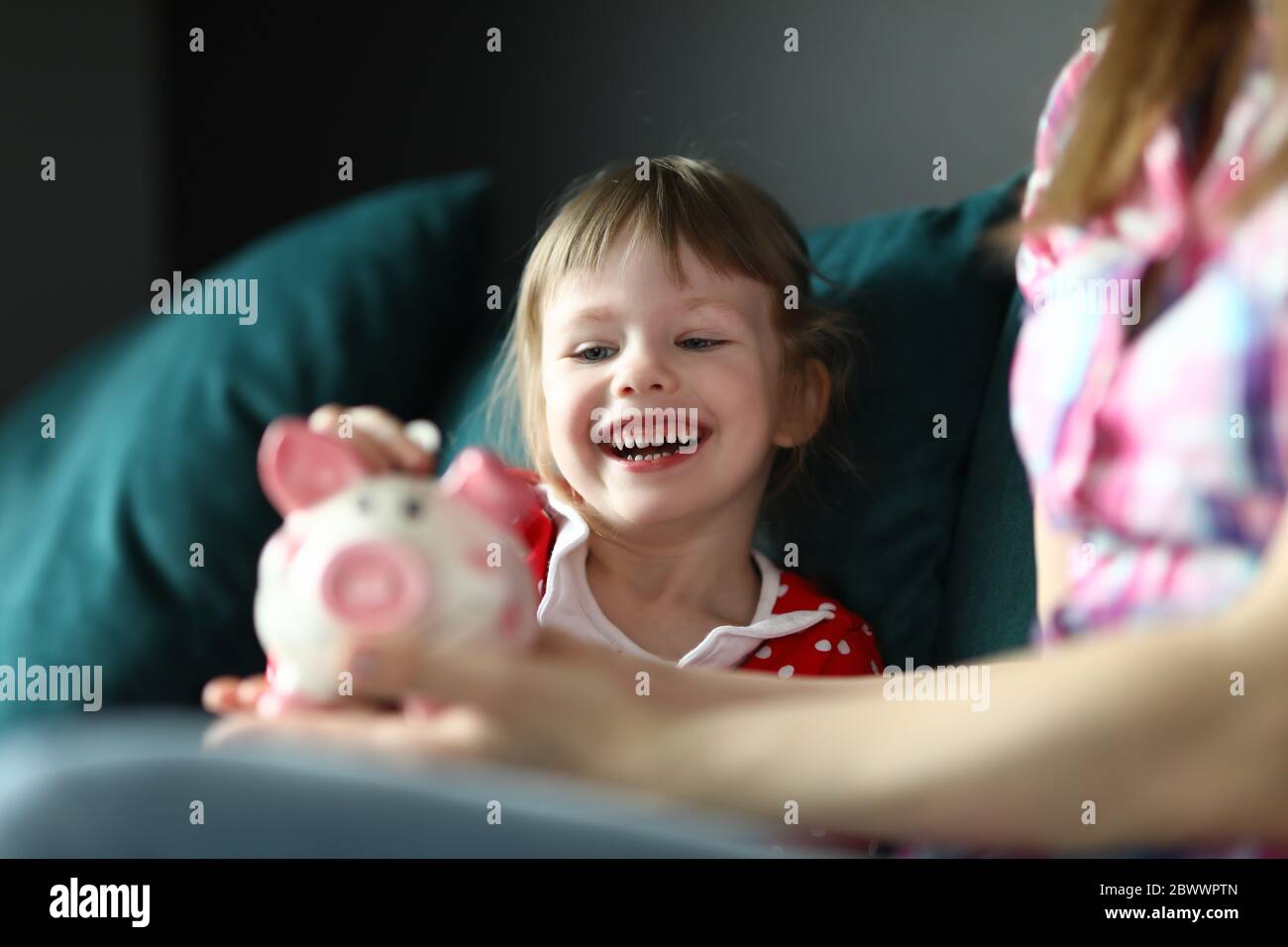 Little girl laughs and puts coin in piggy bank Stock Photo - Alamy