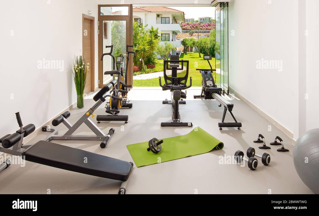 Modern concept of green nature eco style gym. Front view of stylish training room interior in hotel, apartment, house with open air garden window Stock Photo