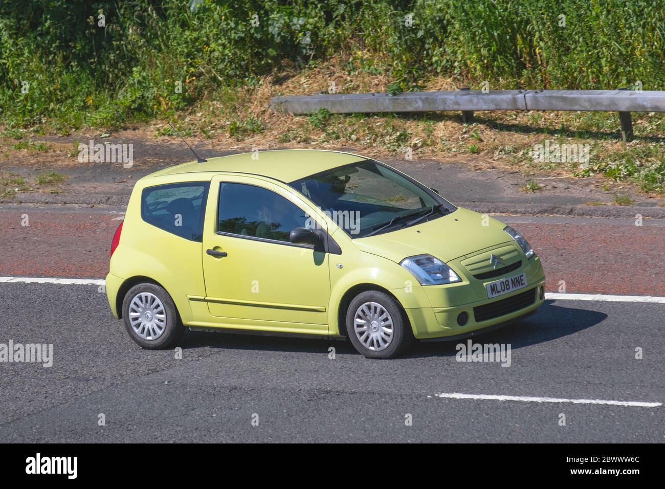 2008 yellow Citroën C2 Cool 2dr small city car ; Vehicular traffic moving vehicles, cars driving vehicle on UK roads, motors, motoring on the M6 motorway highway Stock Photo