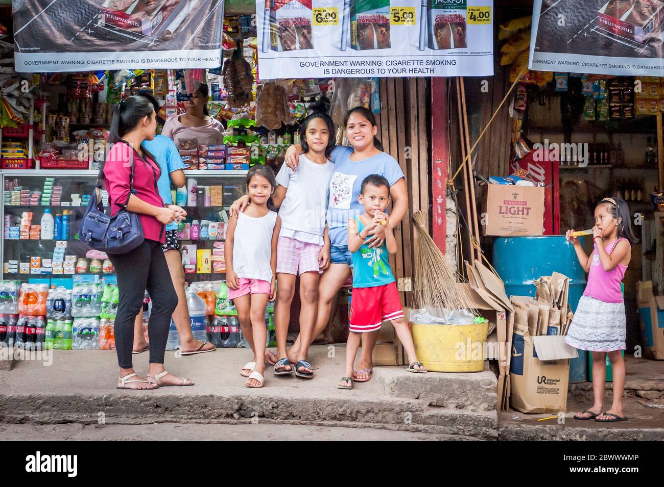 A filipino mother proudly holds her children and poses outside a local convenience store on Coron Island Palawan, The Philippines. Stock Photo