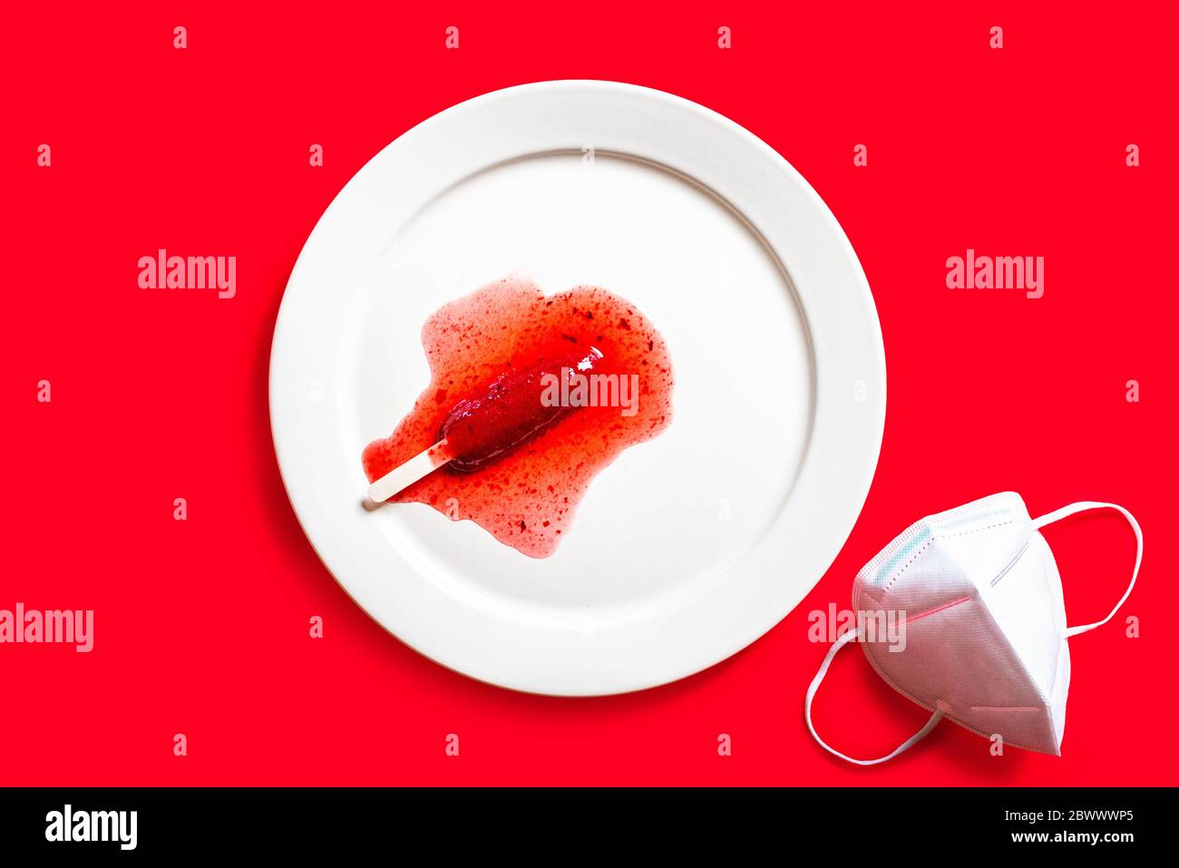 Delicious defrosted strawberry popsicles and medical mask over red background Stock Photo