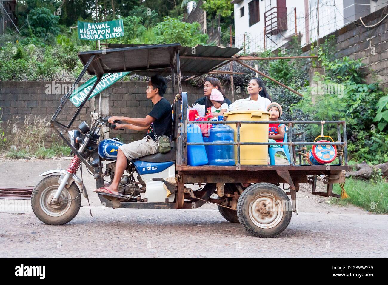 Motorbikes, trikes, lorries, cars and all manner of transport rushes through the dusty main road on Coron Island, Philippines at rush hour. Stock Photo