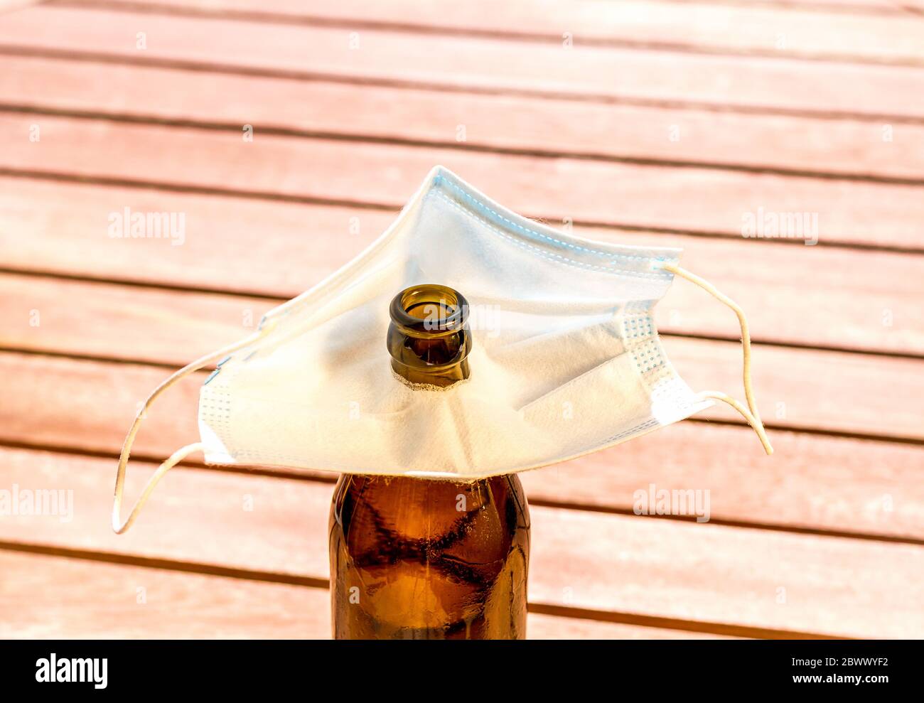 Brown beer bottle and face mask with hole for drinking, top view Stock Photo