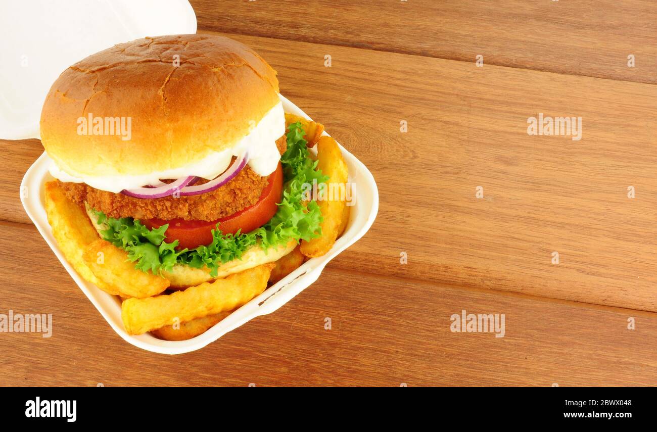 Chicken sandwich and fries in a take away box on a wood background Stock Photo