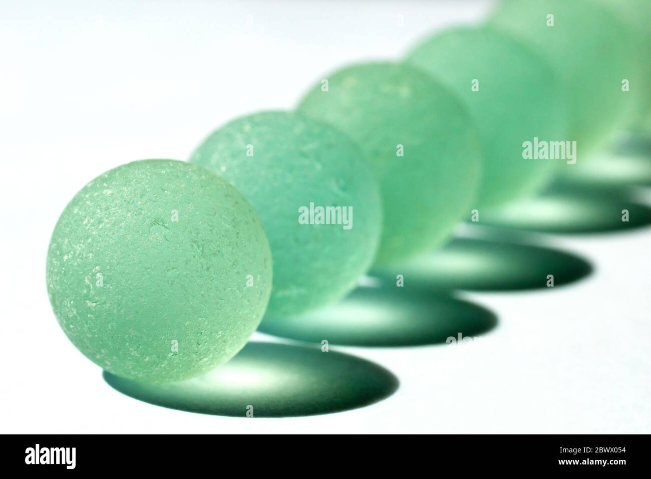 Close up still life of a series of pale green marbles, becoming less focused as they retreat into the distance. Stock Photo
