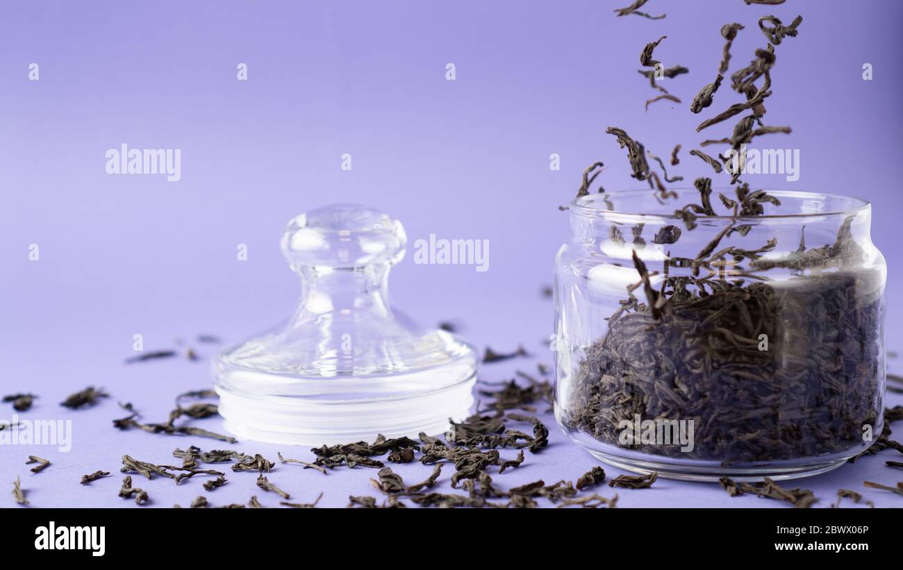 Large leaf black tea in glass jar. Flying tea leaves. Falling dried ...