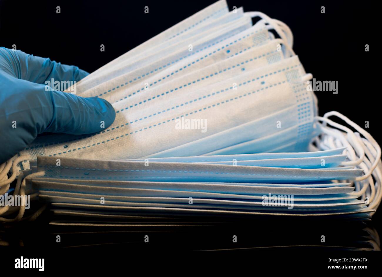 Surgical masks counted by gloved hand. Medical and health care concept