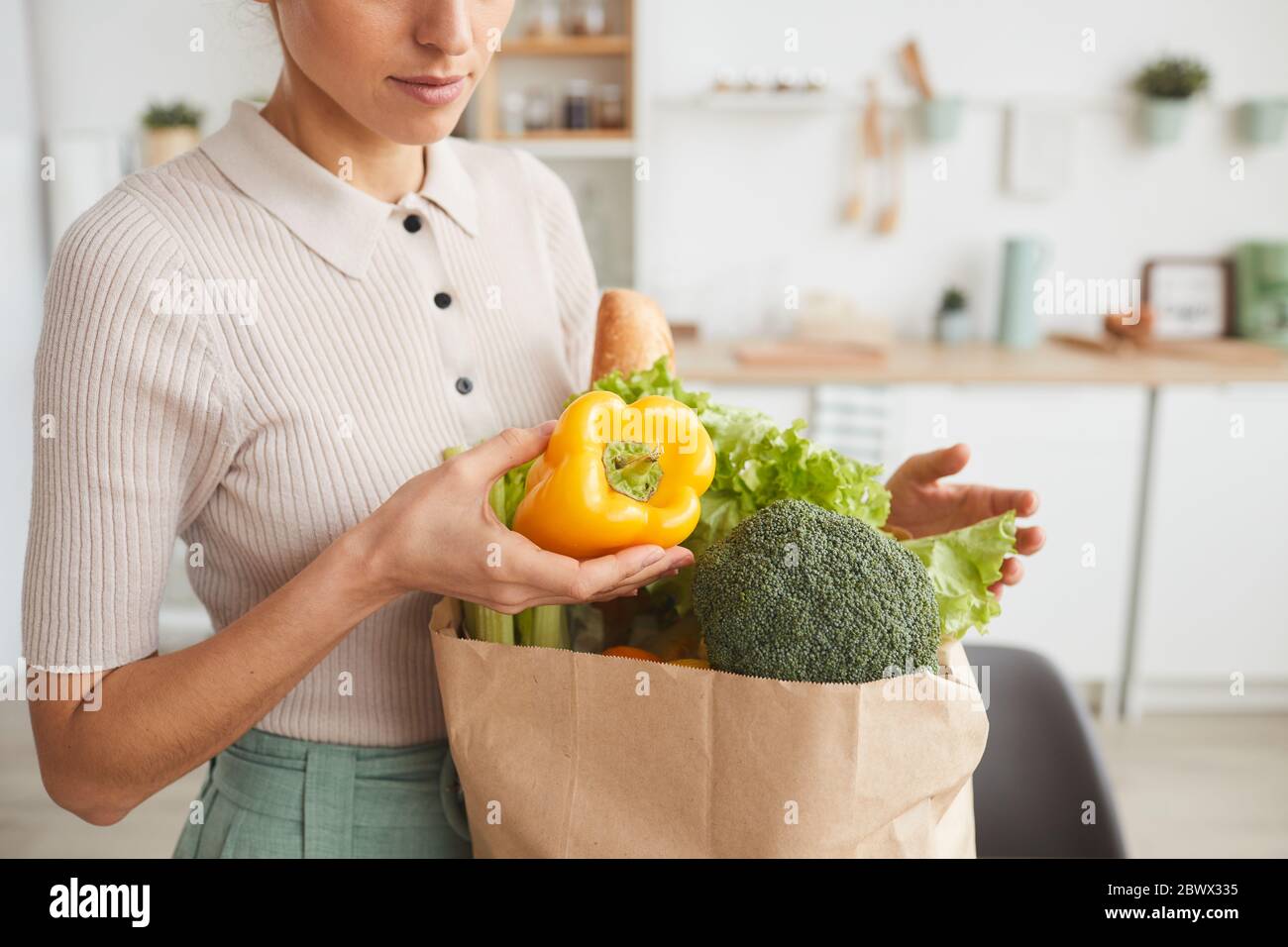 Close-up of woman taking out the fresh vegetables from the paper bag at home Stock Photo