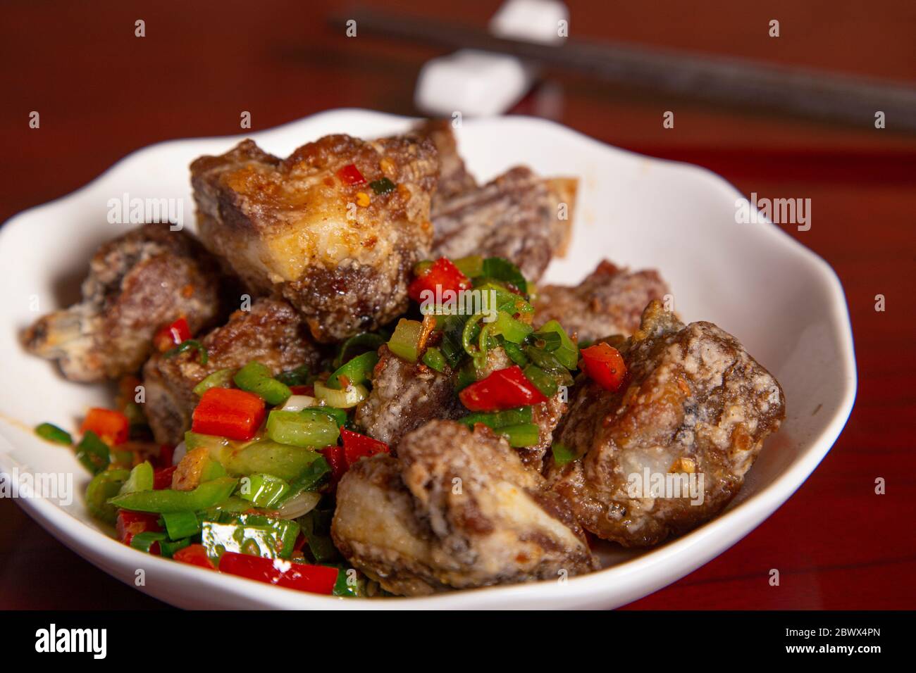 Plate of ribs with salt and pepper with pieces of vegetables. Isolated image. Oriental gastronomy Stock Photo