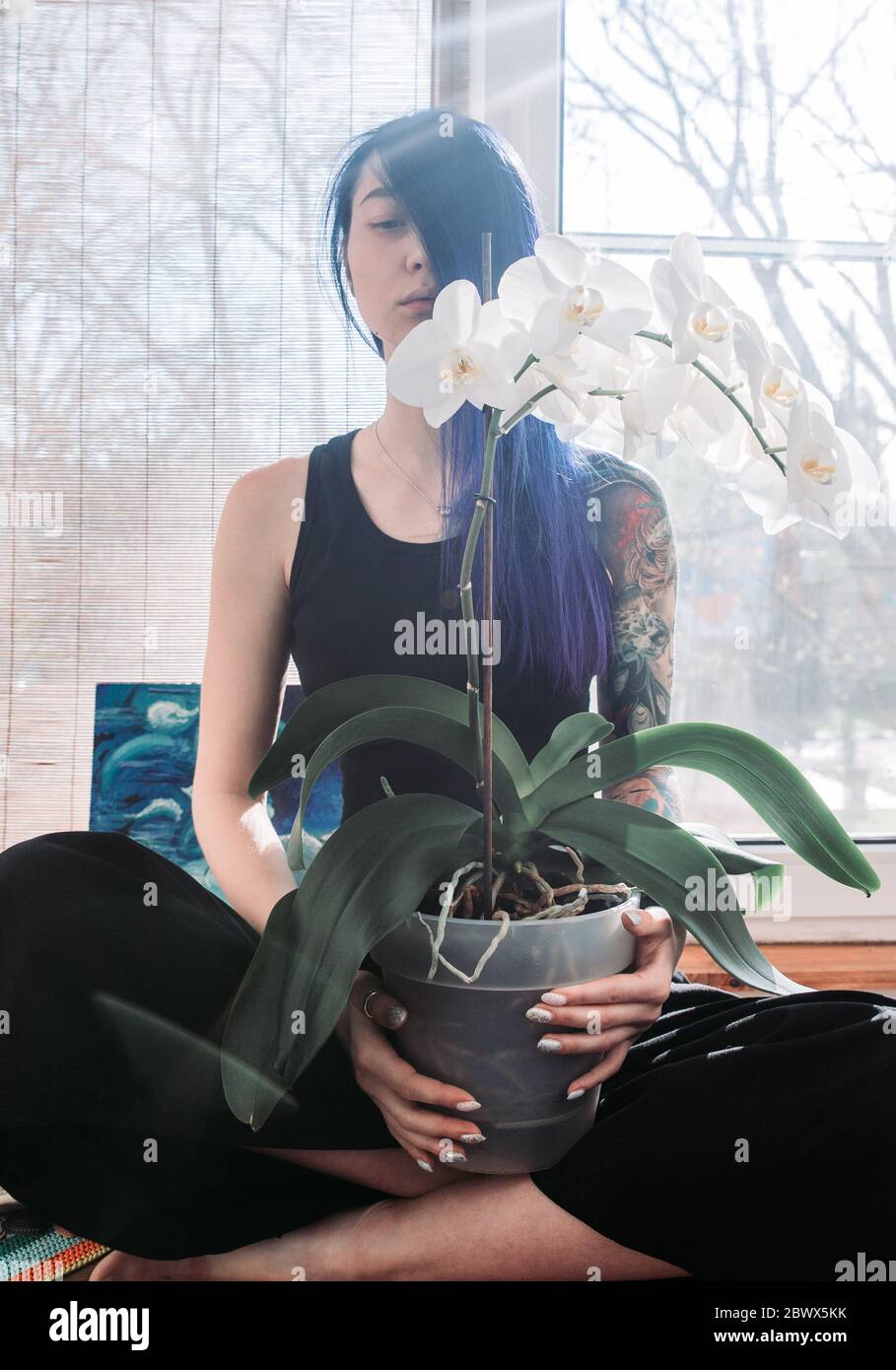 beautiful young woman holding potted plant and smiling at camera ...